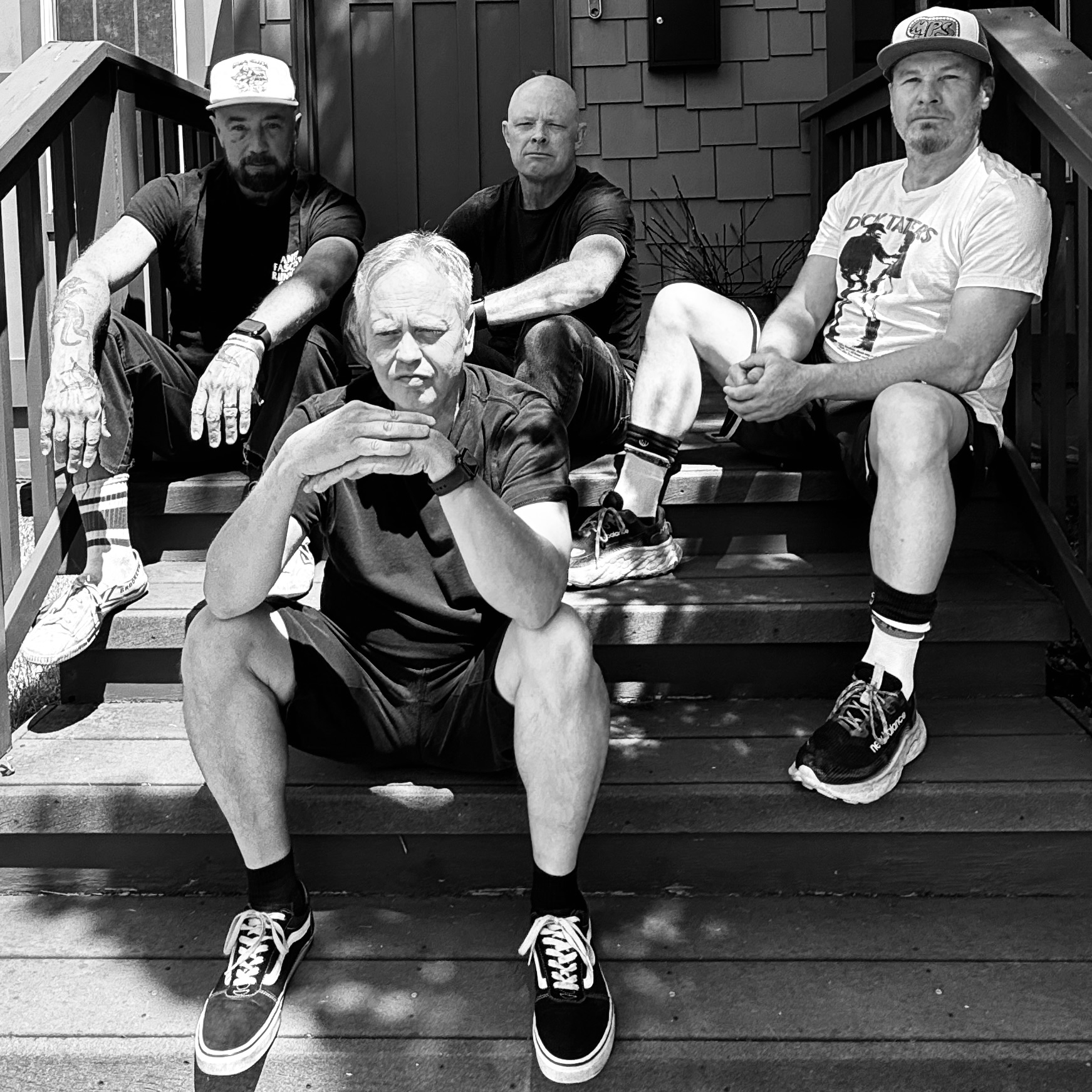 The four members of P.E.S.T. seated together on outdoor steps